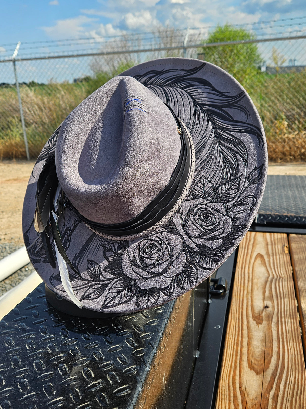 A wide-brimmed cowboy hat with a gray suede-like finish and black floral engraving.